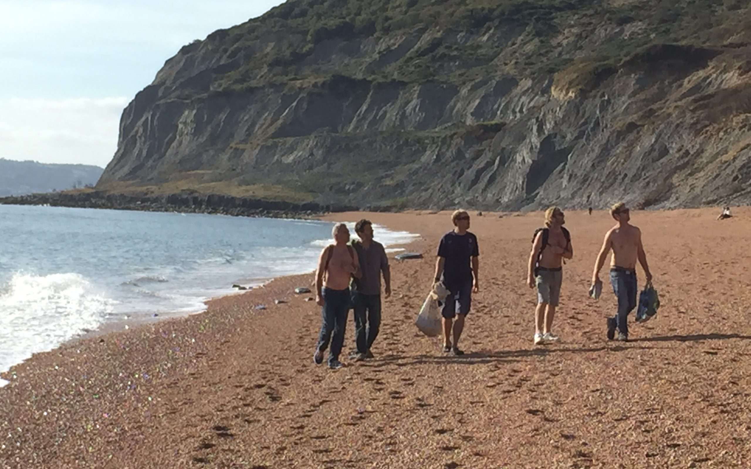Five men enjoying a foraging walk along a shingle beach in dorset